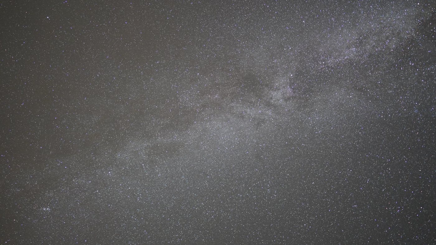 The Milky Way arching across a deep black sky, thousands of stars and visible dust lanes, over a dark site in Tenerife
